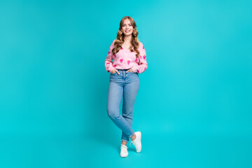 Full body photo of young adorable model candid put hands into jeans pockets and pink pullover heart print isolated on blue color background