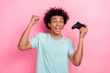 Photo of impressed lucky man dressed blue t-shirt winning playstation game isolated pink color...