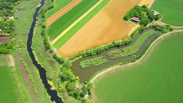A pond and a river in the middle of huge agricultural land creating patchwork