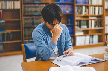 Students feel tired and stressed after working on their laptops and looking for books to study, make reports, find useful information in the university room.