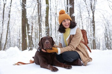 Woman with adorable Labrador Retriever dog in snowy park