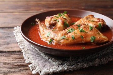 Tasty cooked rabbit meat with sauce and parsley on wooden table, closeup