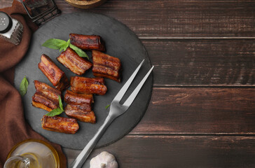 Tasty roasted pork ribs served on wooden table, flat lay. Space for text