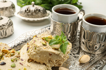 Tasty halva with pistachios and mint served on white table, closeup