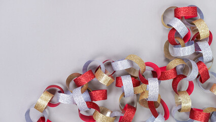 Colorful background with strips of gold silver red sparkling chain garland on grey. Festive...