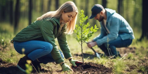 Foto op Plexiglas Volunteering. Young people volunteers outdoors reforestation. Man and woman planting trees in the forest or working in community garden © britaseifert