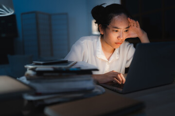 Late-night freelancer, Dedicated Asian woman working overtime on laptop computer, meeting deadlines in the sleepy Night, Businesswoman burning the midnight to working hard, sleep at working desk