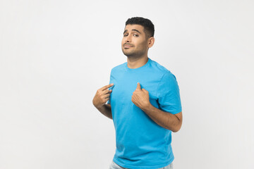 Portrait of unshaven man wearing blue T- shirt standing points at himself, stands self confident,...