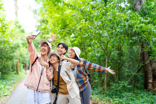 Group of Young Asian man and woman friends travel nature on summer holiday vacation. Happy people enjoy and fun outdoor lifestyle using digital camera taking picture together at forest mountain.