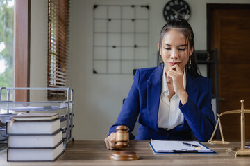 Asian female lawyer or judge providing legal advice and legal services drafting contracts and reading details of clients' cases to study and find solutions to win the case. - obrazy, fototapety, plakaty