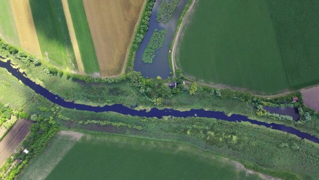 Aerial view of a river and a pond in plain countryside in a shadow of a cloud