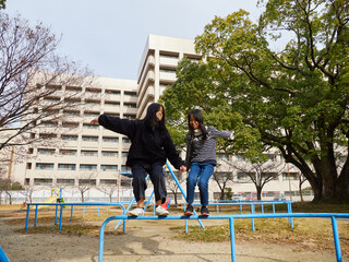 Fototapeta premium 冬の公園で楽しく遊んでいる子供姉妹の姿
