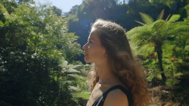 Side View of the Young Charming Curly Blonde Girl Walking Outside on the Jungles. Attractive Positive Lady Outdoor Going, Enjoying the Nature. Traveling and Tourism Concept.