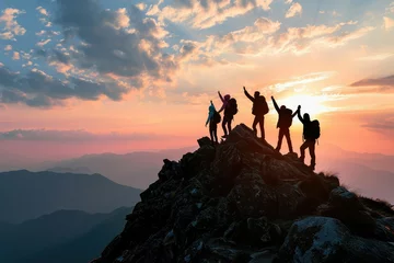 Muurstickers A silhouette of a family team reaching the mountain summit together, their joined hands raised in a victorious gesture, embodying the spirit of unity and shared success. © Lucija