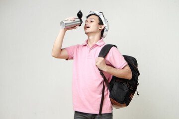 happy asian man backpacker drinking from tumbler bottle. digital nomad and travelling concept. on...