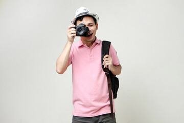 Asian man backpacker taking photo with digital camera. travelling concept. on isolated background