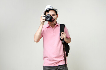Asian man backpacker taking photo with digital camera. travelling concept. on isolated background