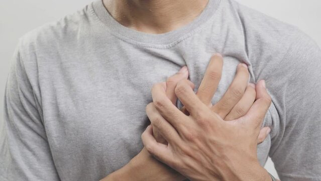 Young man with heart disease, holding hands on chest. Heart attack or stroke. risk of coronary heart disease, diabetes, hyperlipidemia, high blood pressure. isolated.