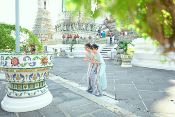 Asian sister wearing Thai traditional clothes dancing at Wat Arun - obrazy, fototapety, plakaty
