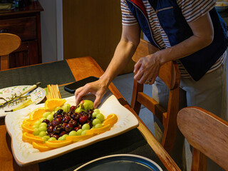 Woman preparing fruit platter on the dinner table. Home cooking and entertainment concept.