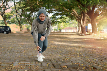 Fototapeta premium Over trained injured asian muslim woman when training exercising or running outdoors. Ankle twist sprain accident in sport exercise running jogging