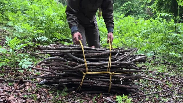 a man tie rope knot to pack dry wooden tree branch wood stick in forest to burn at home for cooking bake traditional hot fresh delicious bread in mud clay oven outside countryside rural village Iran