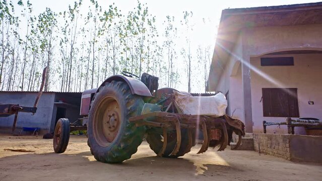 Slow motion Orbit reveal shot of a tractor and some farming equipment in an indian farming household
