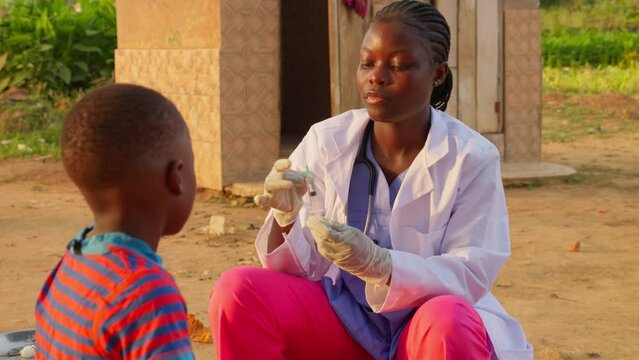 Black female african doctor preparing a syringe giving a vaccine medical treatment to young child in poor remote village of africa slow motion sunset warm light 