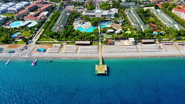 Aerial 4K drone wide top down video of a wooden pier near hotel resort in the city of Kiriş - Kemer (Antalya, Turkey). Filmed in a vibrant summer time. Mediterranean sea.
