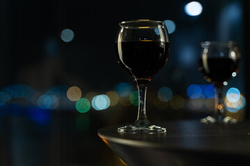 Close-Up of Two Glasses of Red Wine with Night City Bokeh Lights in Background