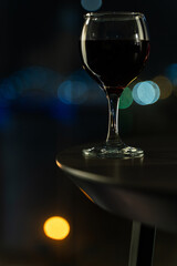 Close-Up of Glass of Red Wine with Night City Bokeh Lights in Background