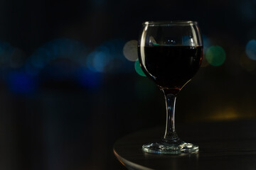 Close-Up of Glass of Red Wine with Night City Bokeh Lights in Background