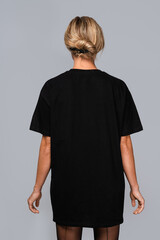 Woman dressed in a black oversized t-shirt with blank space, ideal for a mockup, set against gray...
