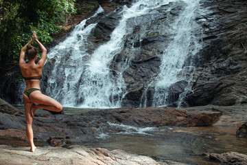 Young Woman in Swimsuit Practicing Yoga Near Waterfall in Rainforest