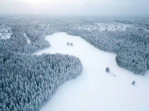 Aerial view of a small settlement in the forest near the lake during winter