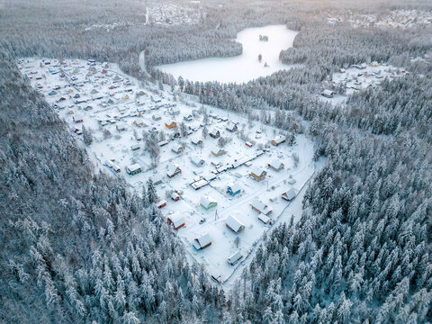 Aerial view of a small settlement in the forest near the lake during winter. A small village in cold weather.
