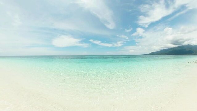 Crystal clear sea water and waves crashing over sandy beach in Mantigue Island. Camiguin, Philippines.