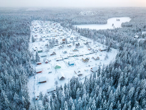 Aerial view of a small settlement in the forest near the lake during winter. A small village in cold weather.