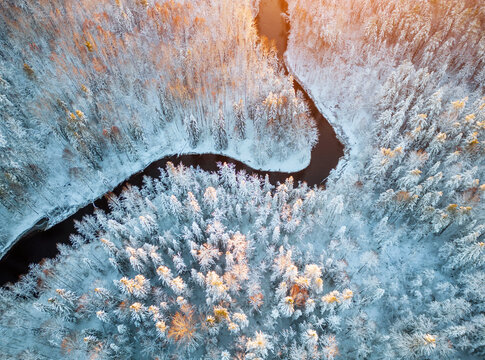 Not a wide river in a cold winter forest at sunset. Beautiful landscape taken from the sky. Republic of Karelia.