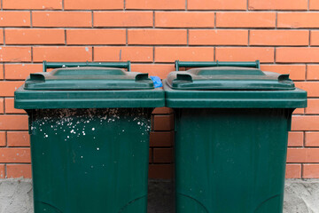 A plastic garbage bin against bricks wall	