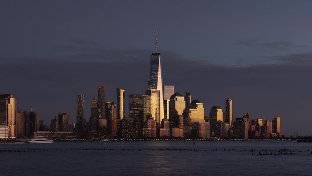 New York City skyline from Hudson River with World Trade Center skyscrapers and illuminated buildings of Lower Manhattan. Timelapse of Financial District from sunset to nightfall