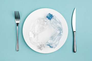 Bottle on the plate and other plastic waste on blue background