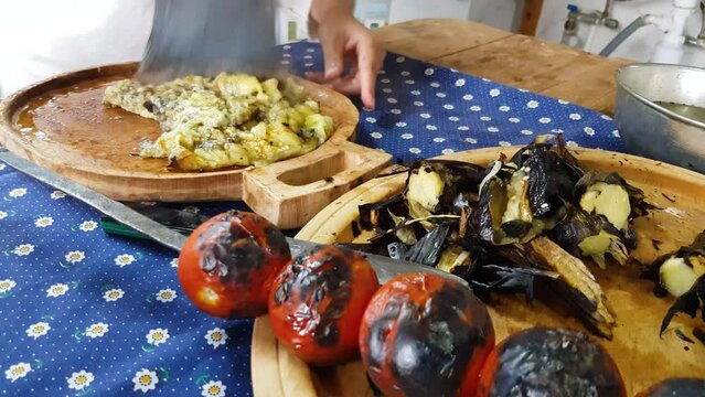 Axe chopping grill eggplant on wooden dish barbecue tomato burn skin pill off vegetable vegan food Persian cuisine of Iranian people in Gilan province Iran mix wrap tasty garlic wonderful scenic local