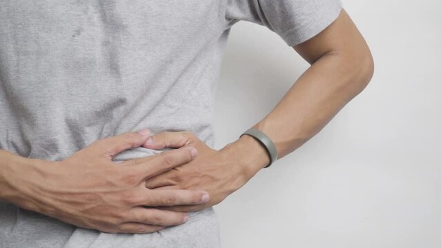 Sick Asian man experiencing stomach ache, pain and discomfort, severe abdominal pain, left kidney infection or appendicitis, pain in the left side of the stomach instead of the right