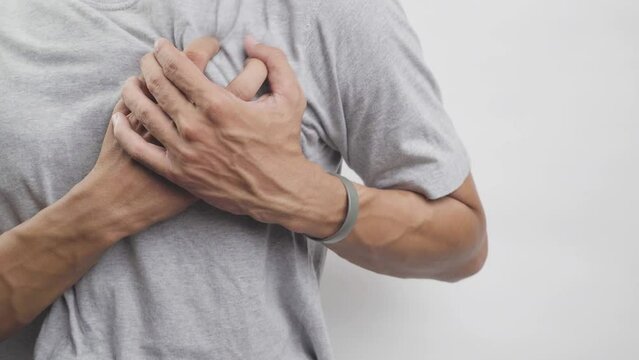 Young man with heart disease, holding hands on chest. Heart attack or stroke. risk of coronary heart disease, diabetes, hyperlipidemia, high blood pressure. isolated.