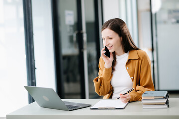 Young woman typing on tablet and laptop while sitting at the working white table office
