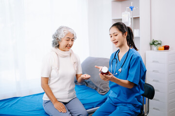 Doctor and Asian elderly patient who lie on the bed while checking pulse, consult and explain with nurse taking note in hospital wards.