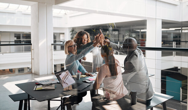 Businesspeople laughing and high fiving together after a meeting