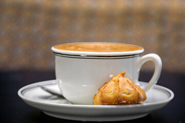 Traditional French macaron cookie and a cup of latte, coffee with milk served at breakfast at an artisanal bakery in Strasbourg, Alsace, France