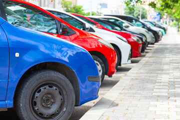 Cars are parked on the side of the asphalt road in the city.